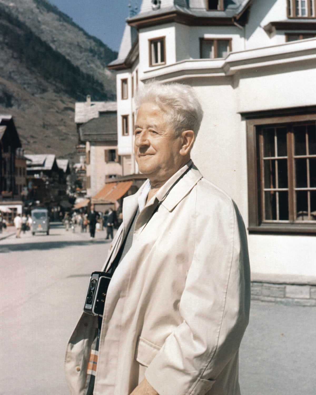 Man with a camera standing on a street with mountains in the background